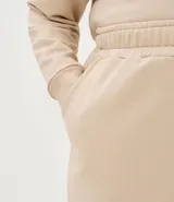 Pantalón de corte wide leg en color beige, con cintura elástica, bolsillos laterales y abertura en el ruedo. Confeccionado en tejido de algodón y poliéster con caída amplia.