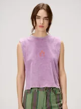 Musculosa crop de algodón con efecto acid wash en color lila, cuello redondo, hombreras marcadas y pequeño bordado central en el pecho.