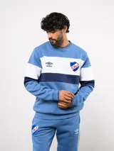 Buzo de cuello redondo confeccionado en felpa, con diseño de bloques de color en azul, rojo y blanco. Presenta el logo de Umbro y el escudo del Club Nacional de Football bordados en el frente.