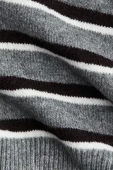 Sweater de punto gris con rayas horizontales en tonos gris oscuro y blanco. Presenta cuello polo blanco y tapeta frontal con cuatro botones marrones. El calce es corto y holgado, con hombros caídos.