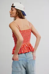 Musculosa de cuadros vichy rojos y blancos, con cuerpo fruncido elastizado, escote recto, tirantes finos y diseño peplum con vuelo en el ruedo.