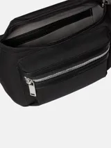 Riñonera negra con exterior de poliéster reciclado y ribetes de piel sintética. Presenta un bolsillo exterior frontal con cierre y un bolsillo interior con ranura. La correa es ajustable con hebilla y el logo de Calvin Klein está grabado en el ribete del bolsillo frontal.