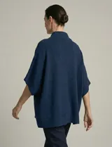 Capa tejida color fucsia, con cuello alto abotonado y mangas cortas estilo japonesa. Tejido de punto grueso.