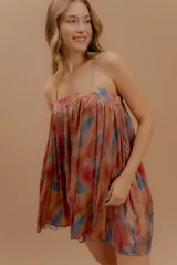 Vestido corto de silueta amplia y diseño fluido, con breteles finos y escote recto. Presenta un estampado abstracto en tonos cálidos y profundos con efecto acuarelado.