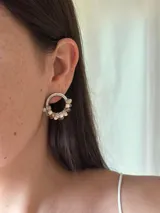 Aro de plata con forma de herradura, decorado con pequeñas cuentas facetadas en tonos rosados y beige.