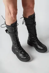 Borcegos negros de ecocuero con cordones y hebilla lateral.