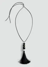 Collar largo con cordón negro y colgante compuesto por cuentas de diferentes materiales y colores (verde, negro y perla) rematado con una borla de flecos negros.