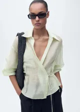 Camisa color verde agua, de corte cruzado con lazo en la cintura, cuello camisero, manga larga y bolsillo de parche en el pecho.