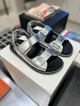 Sandalias plateadas con tiras de velcro ajustables y suela track negra con pespuntes blancos.