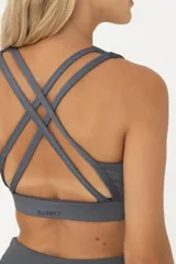 Top deportivo gris con breteles finos y tiras cruzadas en la espalda.