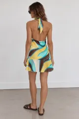 Vestido corto de diseño abstracto con estampado en tonos marrón, amarillo, celeste y blanco, con escote halter drapeado y falda con vuelo.