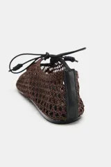 Zapato plano tipo bailarina marrón con diseño de calados en todo el cuerpo, terminación en punta cuadrada y cierre de lazo en la parte delantera.