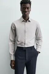 Camisa de manga larga para hombre, color gris claro con micro-estampado de cuadros sutiles. Presenta cuello italiano y cierre frontal de botonadura.