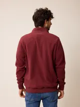 Campera de polar bordó con cierre frontal completo, cuello alto y puños elásticos. Presenta un diseño liso con logo bordado en el pecho.