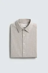 Camisa de corte slim fit confeccionada en tejido de algodón, con estampado de cuadros pequeños en tonos beige y blanco. Presenta cuello italiano, manga larga con puños abotonados y cierre frontal con botones.