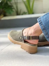 Zuecos de cuero color verde seco, con hebilla lateral y suela de goma.