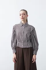 Camisa a rayas azules y blancas de manga larga, con cuello clásico y puños abotonados. Presenta un diseño entallado en la cintura.