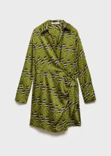 Vestido corto de tejido satinado con estampado geométrico en tonos verdes, negros y blancos. Presenta cuello camisero, mangas largas y un diseño cruzado que se ajusta en la cintura mediante un lazo lateral.