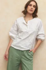 Blusa blanca de algodón bordada, de manga larga con cuello mao y mangas abullonadas con elástico en los puños.