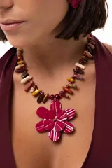 Collar corto con dije central de flor doble en color bordó con detalles pintados a mano. La cadena está compuesta por piedras naturales en tonos tierra y bordó, intercaladas con pequeñas cuentas rojas.