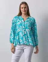 Blusa de gasa estampada marca Zac & Rachel. Tiene cuello a la base, escote en V con apertura y botones. Las mangas son 3/4 con frunce. Tiene detalle de crochet en hombros y delantera.