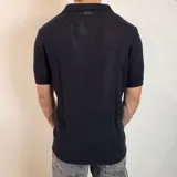 Chomba de tejido de punto con textura, color beige, de manga corta y cuello polo con cierre frontal parcial.