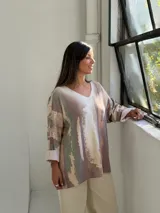 Sweater de punto con diseño abstracto en tonos tierra, verde y beige, de corte holgado, cuello en V y mangas largas con puños vueltos.