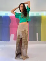 Falda larga blanca de lino y algodón con estampa exclusiva en cobre laminado. Corte asimétrico, tajo central y un bolsillo lateral. Cierre frontal con broches a presión.