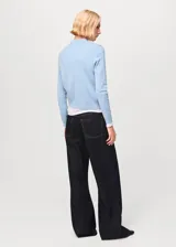 Jersey de punto fino en mezcla de algodón y lana, color celeste, con cuello polo y cierre frontal de botones.