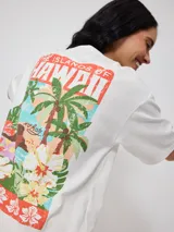 Remera blanca de algodón con estampado en la espalda de palmeras, flores y texto 'The Islands of Hawaii'.