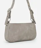 Cartera tipo baguette de PU color beige claro, con acabado liso y detalles de apliques metálicos tipo tachas y argollas en color gunmetal. Presenta un bolsillo frontal con cierre y un tirador de cuero sintético colgante. Incluye asa corta ajustable con hebilla.