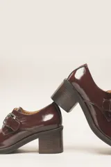 Zapato de cuero vacuno color borgoña con acabado charol, taco cuadrado de 4 cm y hebilla lateral.