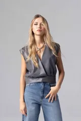 Top color beige de simil cuero liviano, con escote cruzado y acceso por cierre invisible lateral. Sin mangas con espalda cerrada y frunces en hombros.