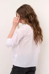 Blusa celeste de manga larga con delicados bordados florales en tono más claro en la zona del pecho y mangas. Presenta escote en V y puños elásticos abotonados.