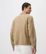 Sobrecamisa de sarga de algodón en color beige, de corte amplio y estructurado, con cuello camisero, mangas largas, cierre frontal de botones ocultos y grandes bolsillos frontales con solapa.