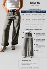Pantalón de jean estilo palazzo, color gris claro, con corte amplio y fluido. Presenta un dobladillo ancho fijo en la botamanga, cierre frontal con botón y cremallera, y trabillas para cinturón. Incluye un cinturón negro con hebilla metálica.