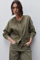 Campera azul marino de algodón, de corte relajado y largo corto, con cuello redondo, cierre frontal con botones metálicos, bolsillos delanteros y mangas largas con puños ajustables.