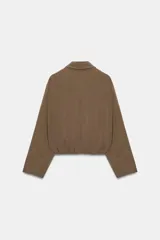 Cazadora tipo bomber color marrón, confeccionada en mezcla de viscosa. Tiene cuello solapa, manga larga, bolsillos de vivo en los laterales y bajo acabado en elástico. Cierre frontal con cremallera metálica.