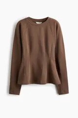 Buzo de felpa con interior cepillado, cuello redondo acanalado y mangas largas raglán. Presenta costuras moldeadoras en la cintura que crean una silueta entallada con efecto peplum.