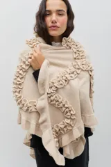 Chal de lana color marrón con diseño envolvente, decorado con volados aplicados en toda la superficie que aportan textura y movimiento.