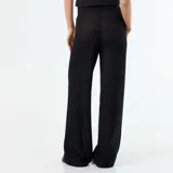 Pantalón de playa color negro, confeccionado en tejido de croché con patrón calado, de tiro medio y corte ancho en las piernas.