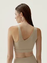 Top deportivo color beige con diseño asimétrico y tirante ancho en un hombro.