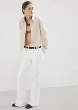 Jeans blancos de tiro alto y estilo flare, confeccionados en tejido elástico de algodón. Presentan diseño de cinco bolsillos, trabillas para cinturón y cierre frontal con cremallera y botón.