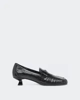 Mocasines de cuero vacuno negro con acabado naplak de efecto arrugado, tacón fino bajo de 3 cm y detalle de placa metálica con la inicial D en la tira frontal.