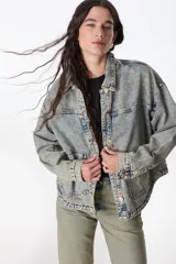 Campera de denim celeste con efecto lavado, corte recto, cuello camisero, cierre frontal con botones metálicos, bolsillos de parche en el pecho y laterales.