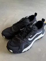 Championes Vans Crosspath XC, color negro, con detalles en gris claro y blanco. Diseñadas para uso todoterreno urbano, cuentan con parte superior de malla de PET reciclado, ante y textiles, tratamiento DWR, suela Vibram XS TREK EVO y entresuela UltraCush™.