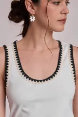 Remera negra sin mangas, tipo musculosa, con escote redondo y ribetes blancos con apliques de perlas en el contorno del cuello y las sisas.