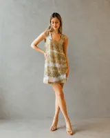 Vestido corto de silueta relajada, completamente bordado en lentejuelas con diseño de franjas horizontales en tonos dorados y plateados. Presenta escote redondo y breteles anchos.