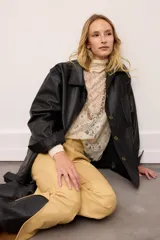 Chaquetón de cuero negro oversized, con corte recto y bolsillos delanteros. Presenta un bordado en los bolsillos inspirado en la costa atlántica.