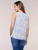Blusa de lino y rayón color beige con estampado floral en tonos celestes, sin mangas, con escote redondo y detalle de tres aros metálicos plateados entrelazados en el frente.